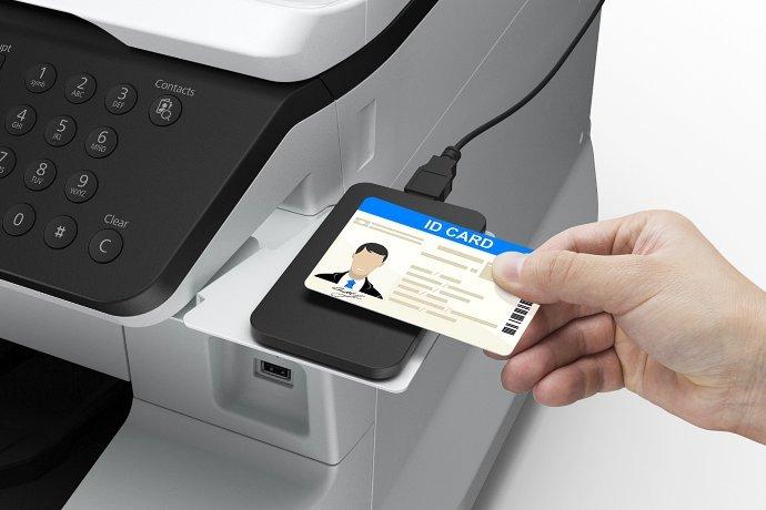Jemand hält eine Sicherheits- oder Ausweiskarte an einen Drucker.
