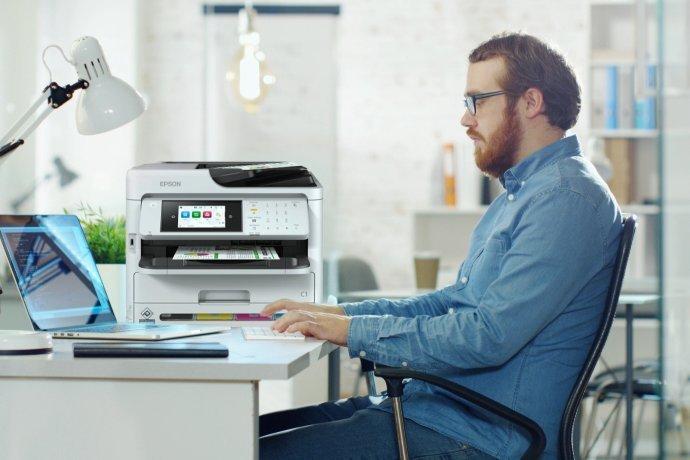 Ein Mann, der mit seinem Laptop an einem Schreibtisch sitzt.
