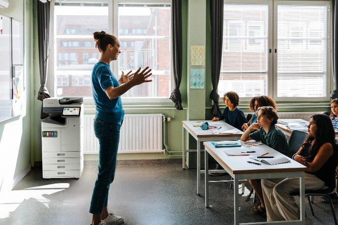 Ein Lehrer, der vor einer Klasse kleiner Kinder steht.
