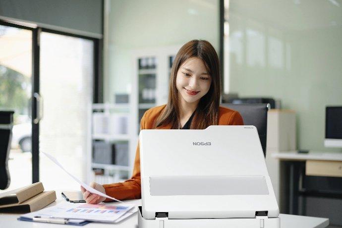 A woman sat at a desk using a scanner.