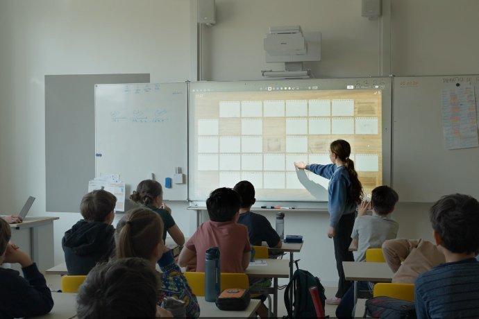 A teacher using a projector in front of a class.