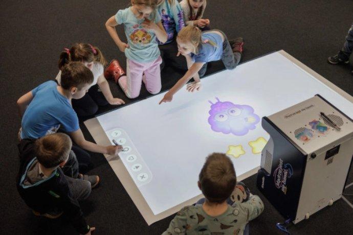 An Epson printed projecting onto a table surface, kids are interacting with it.