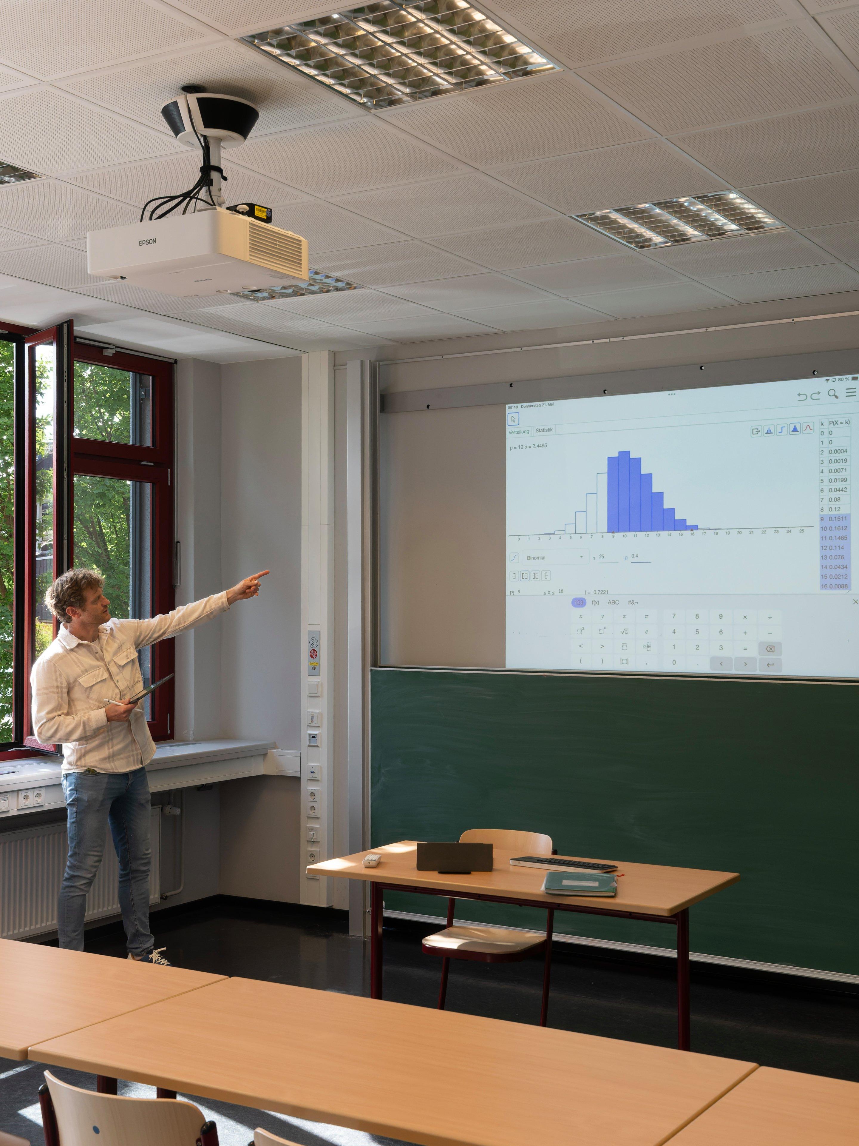 Ein Mann, der auf die Projektion eines Diagramms an der Wand zeigt