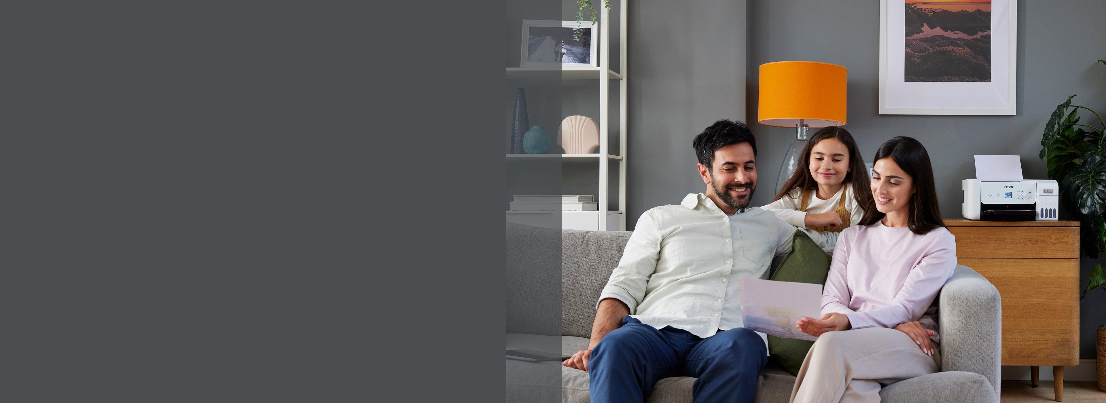 A family of three sits on a cozy gray sofa in a modern living room. They smile while reading a document, with a printer and bright decor in the background.