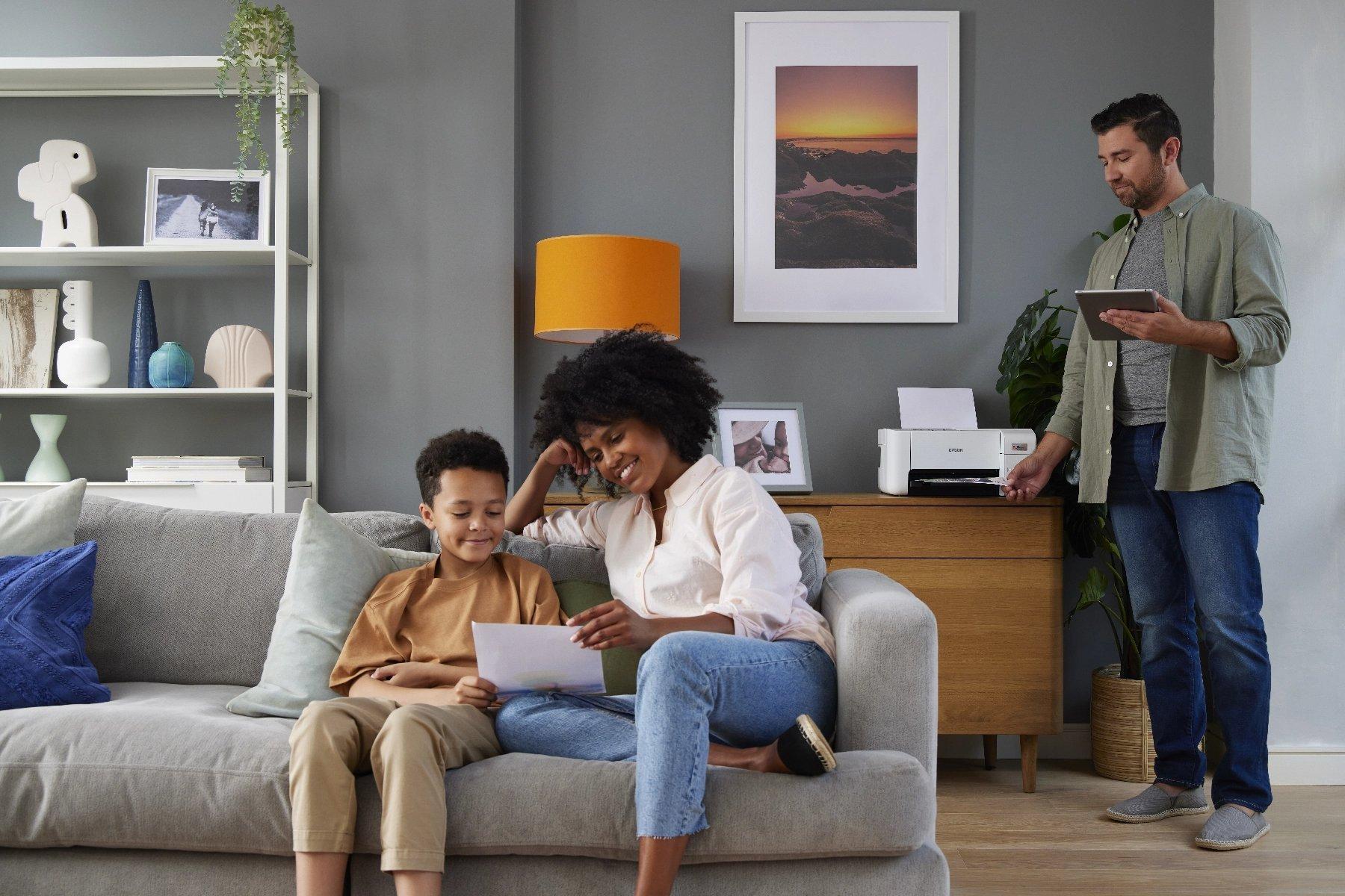 A woman and child on a sofa, holding a photo. The room's cozy ambiance includes framed art, shelves, and a warm orange lamp.