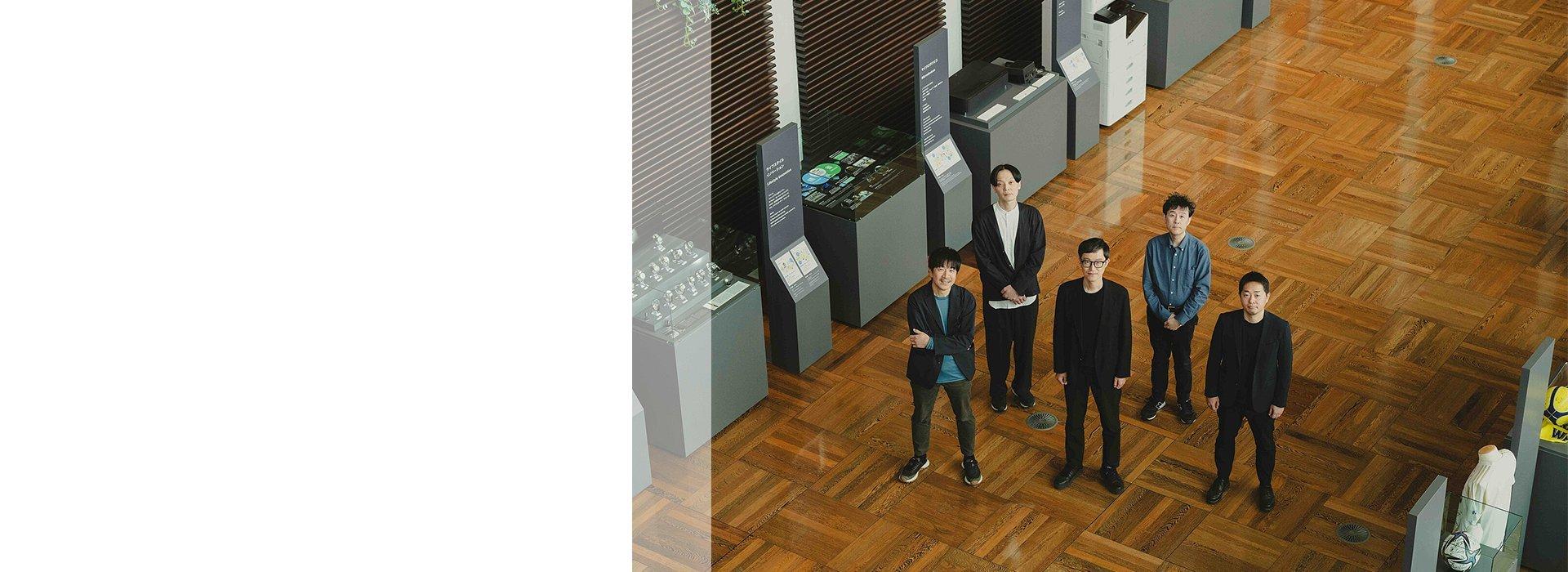 Five Epson employees standing on a wooden floor in a museum display area.