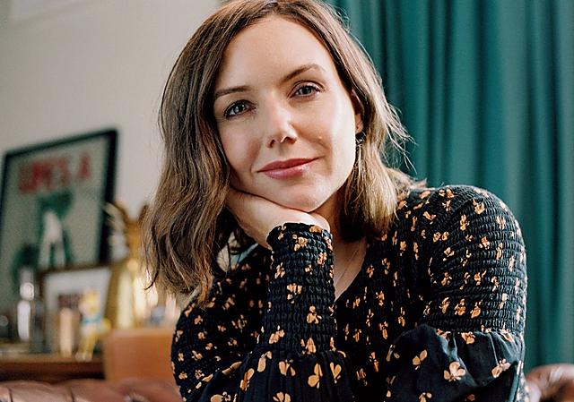 Woman wearing a black floral top is smiling at the camera. Her name is Sali Hughes, a journalist and broadcaster.