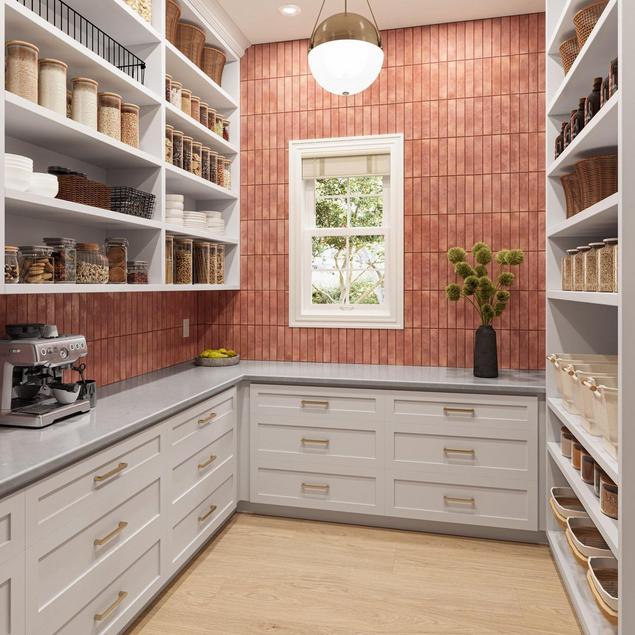 Walk-in pantry with red ceramic backsplash tile, gray marble countertop, and white cabinets.