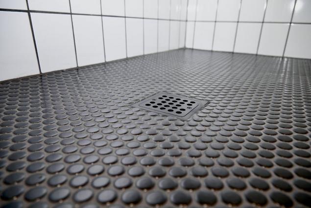 Close-up of black penny tile shower floor with gray grout.