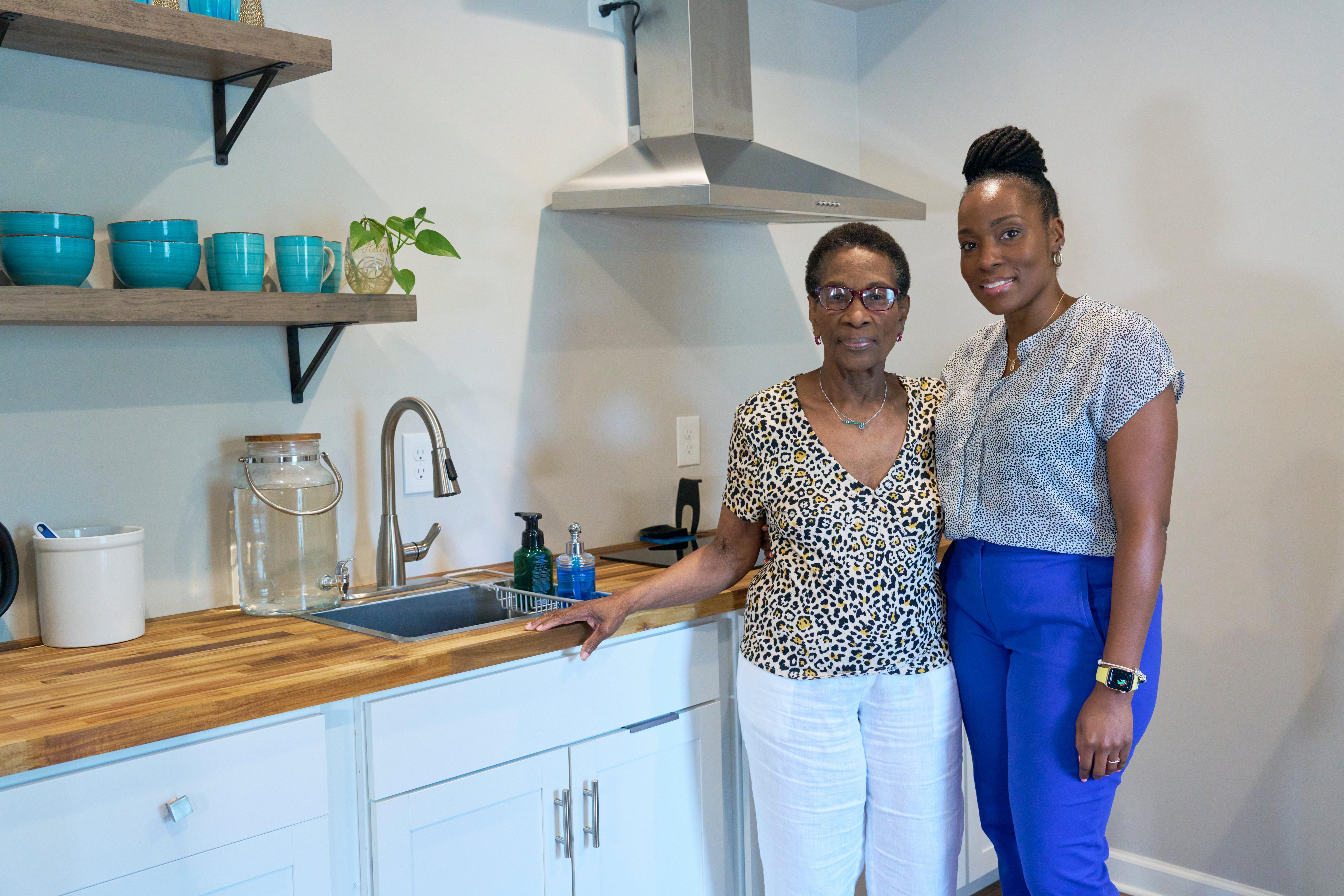 Two women standing infront of a kitchen.