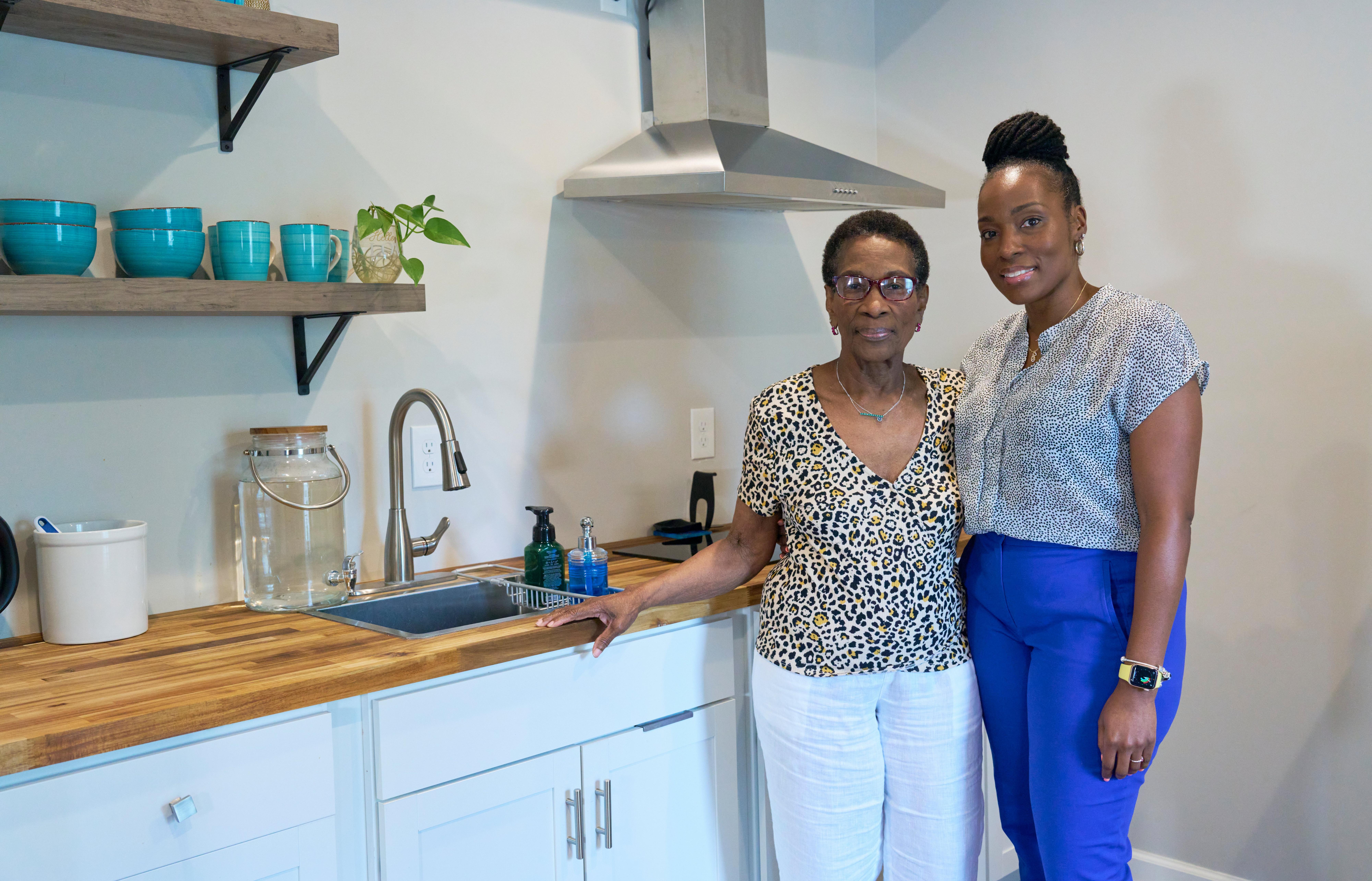 Two women standing infront of a kitchen.