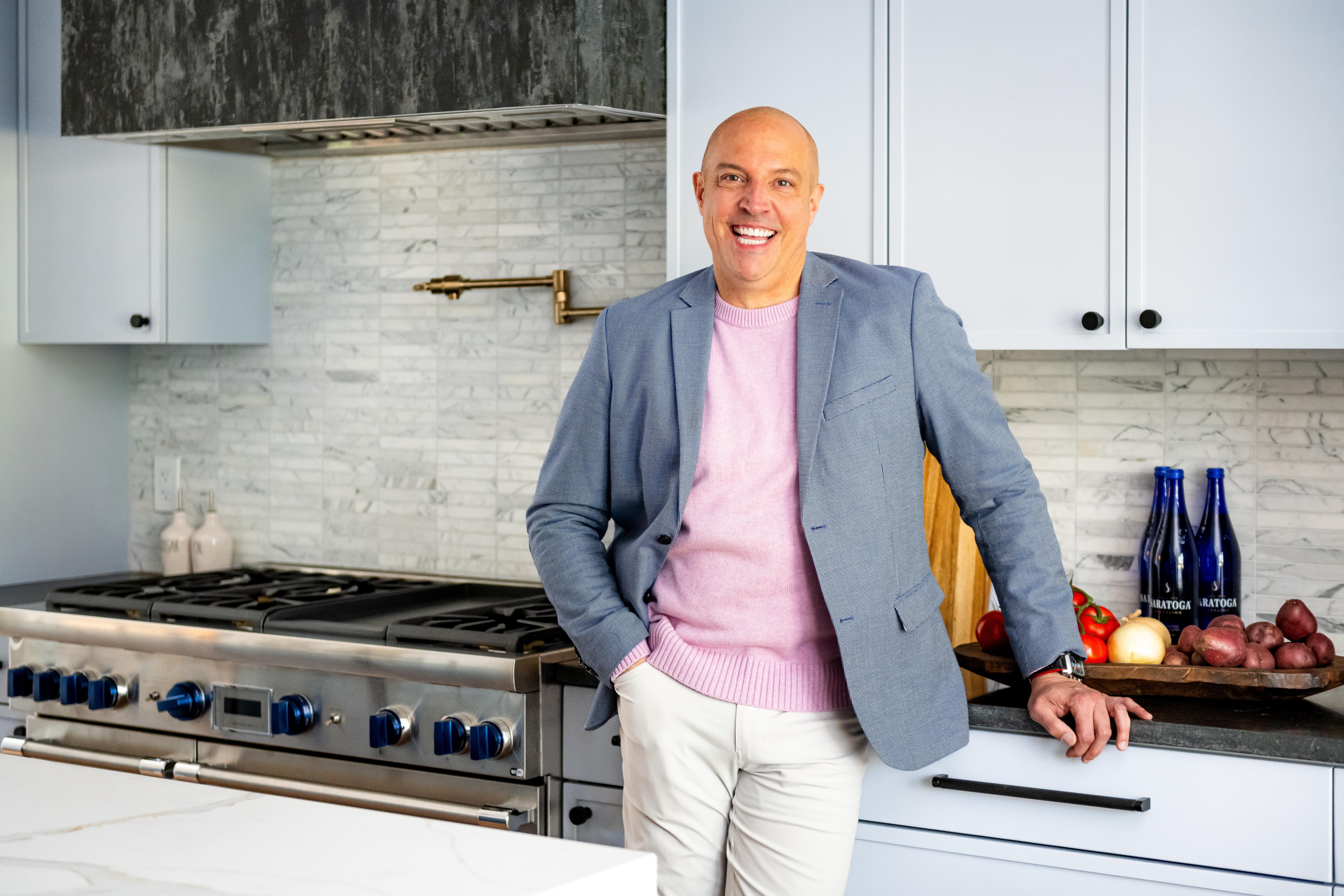 Creighton posing in his renovated kitchen in front of the marble backsplash