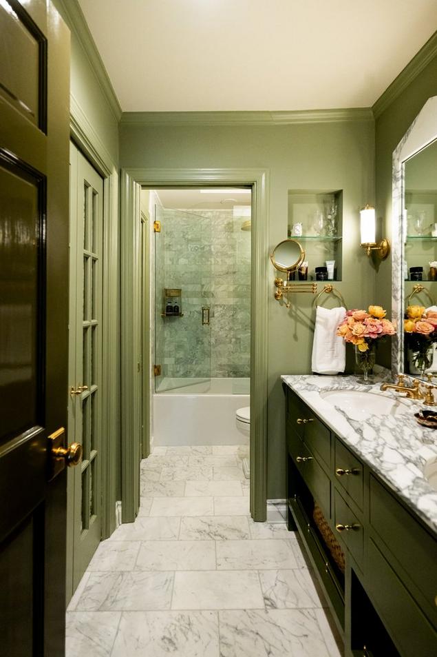 Primary bathroom with tonal green walls, marble floors, and a view of green marble shower wall tile.
