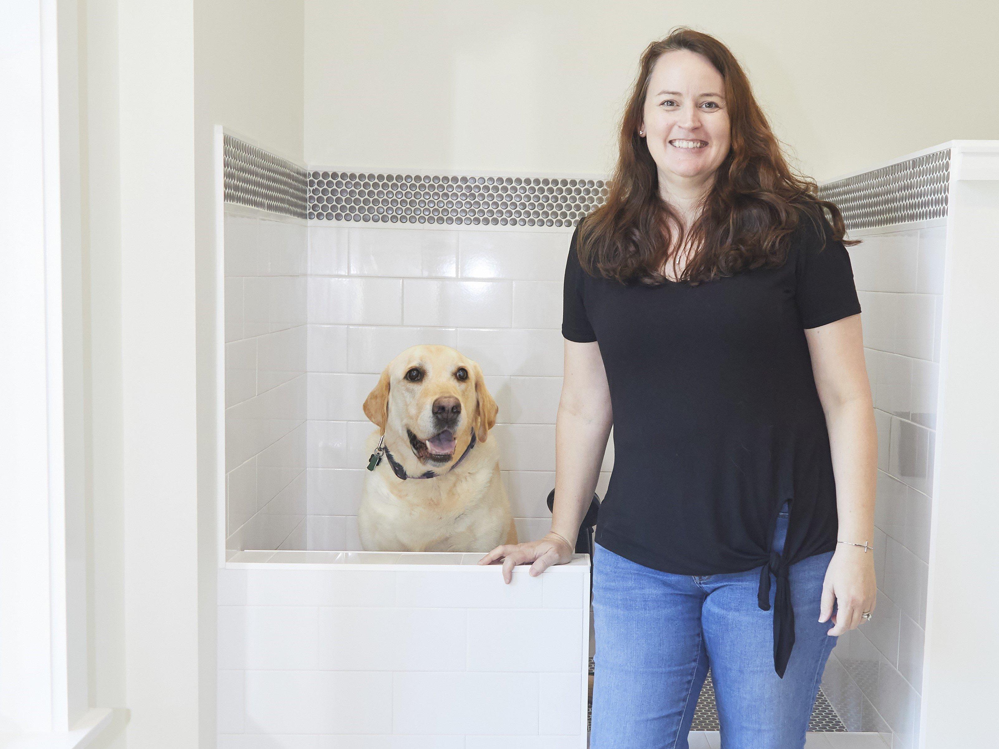 Shannon and her dog in pet washroom next to the white subway tile dogbath.