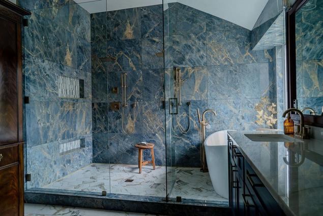 Post-bathroom remodel with wet room, dramatic blue wall tile, and hexagon marble look tile flooring.