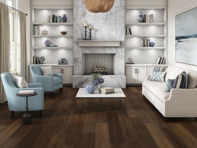 A living room with blue and white furniture, white walls, and darkwood floors.