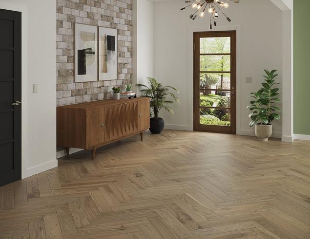 An entry way with herringbone vinyl flooring, a cabinet, and glass door.