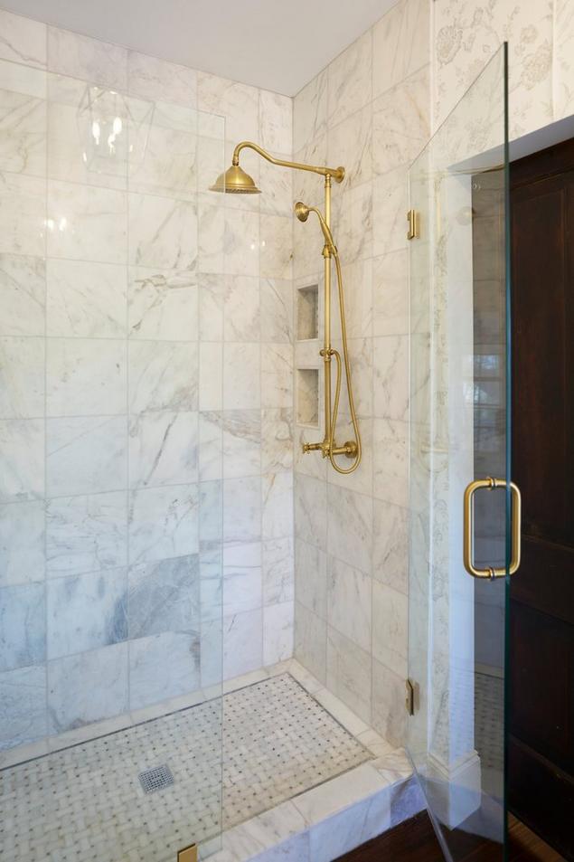 White marble shower with glass door and gold hardware