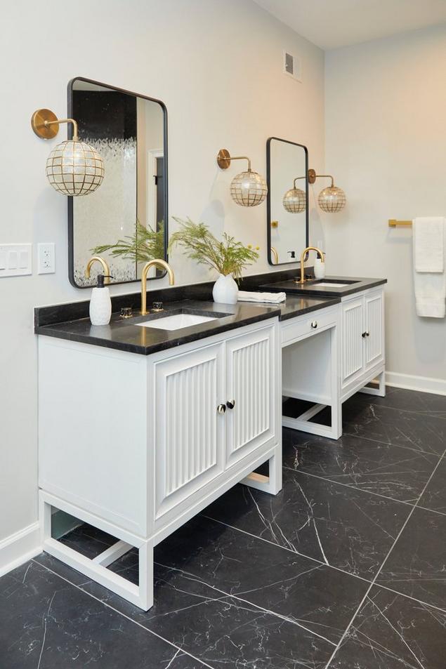 Bathroom with black marble tile floors, double vanity with white cabinets and black marble top.