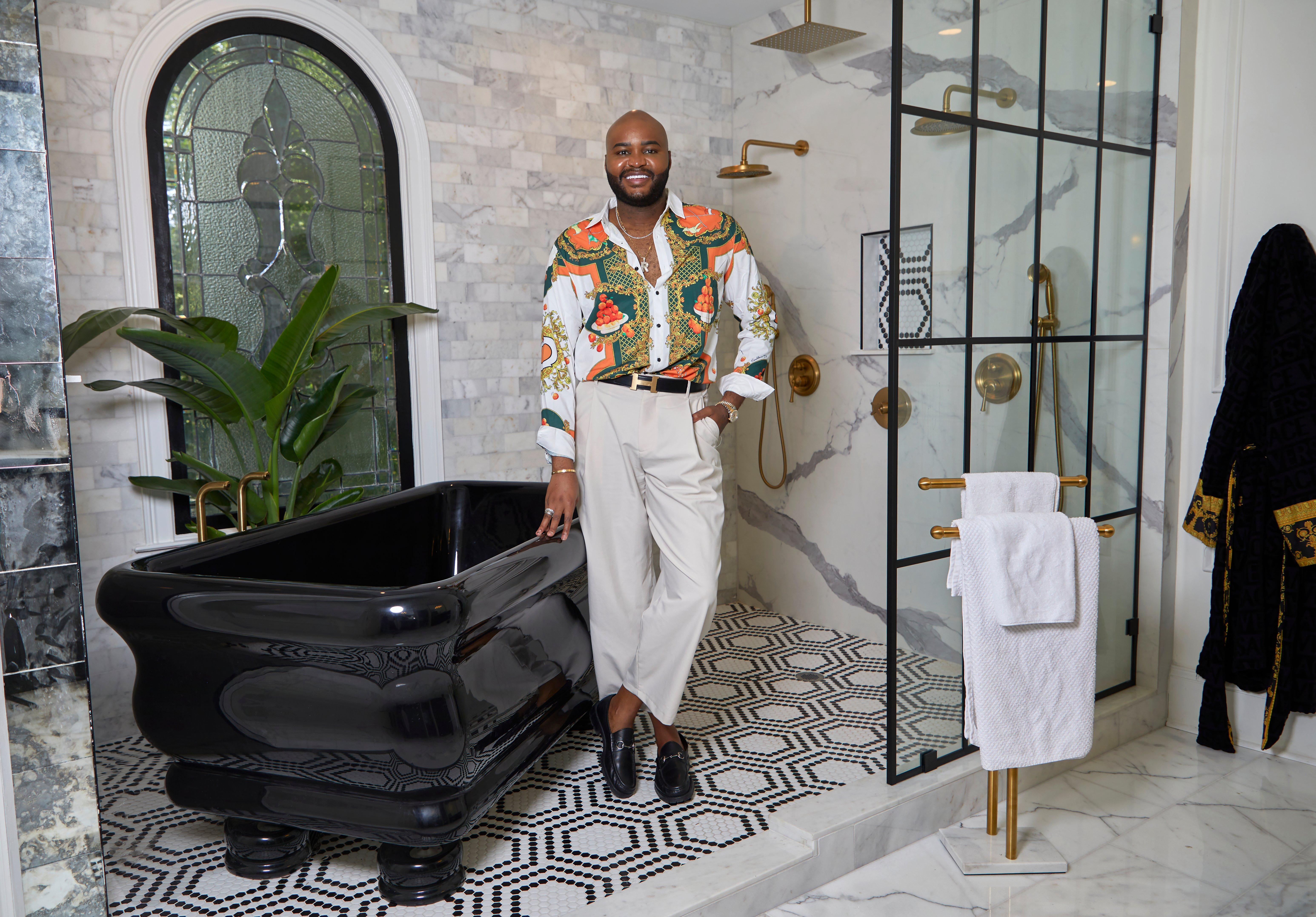 Ron posing against black bathtub in primary bathroom with white marble.