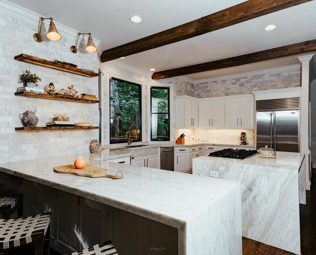 Kitchen with wood beam ceilings, white marble walls and countertops, and floating wood shelves.