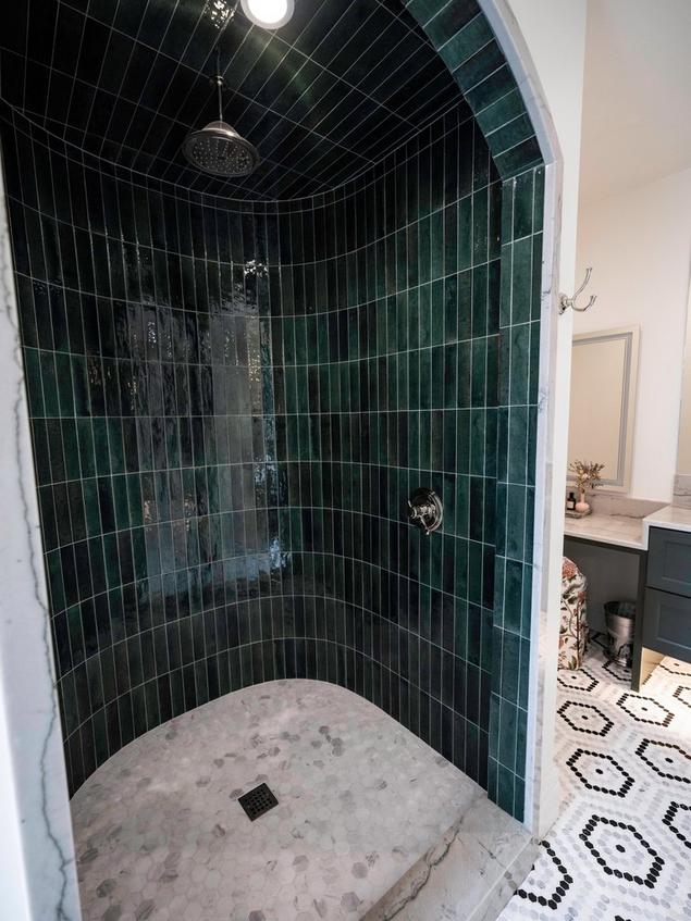 Side view of Chloe's shower with green decorative tile walls and white marble mosaic flooring.