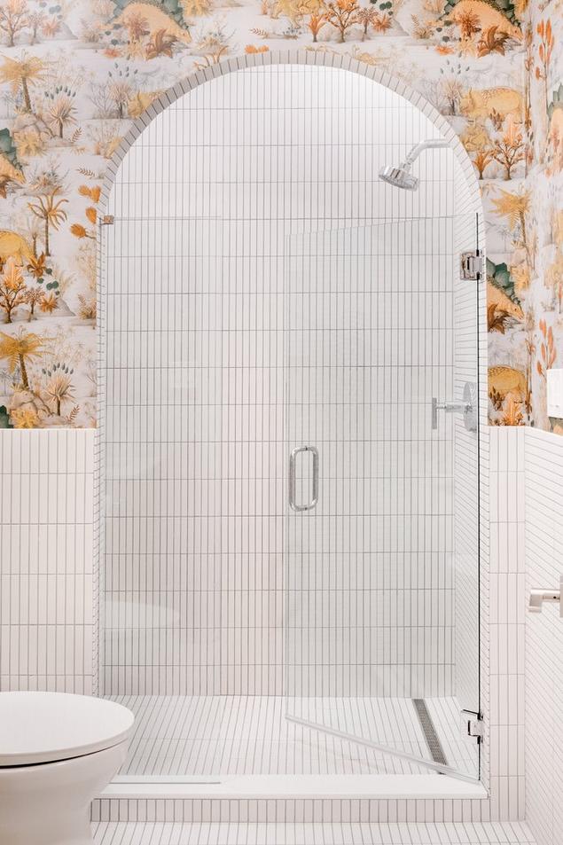 Shower with an arched entrance tiled with stacked porcelain mosaic tile.