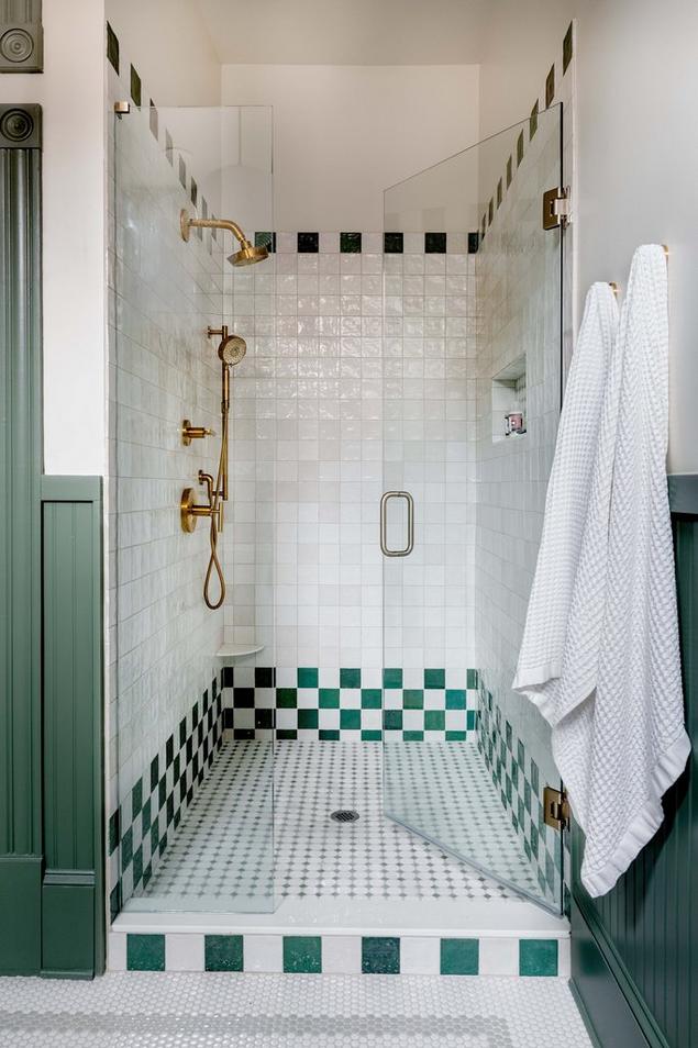 Shower with white and green checkboard tile and a mosaic floor. 