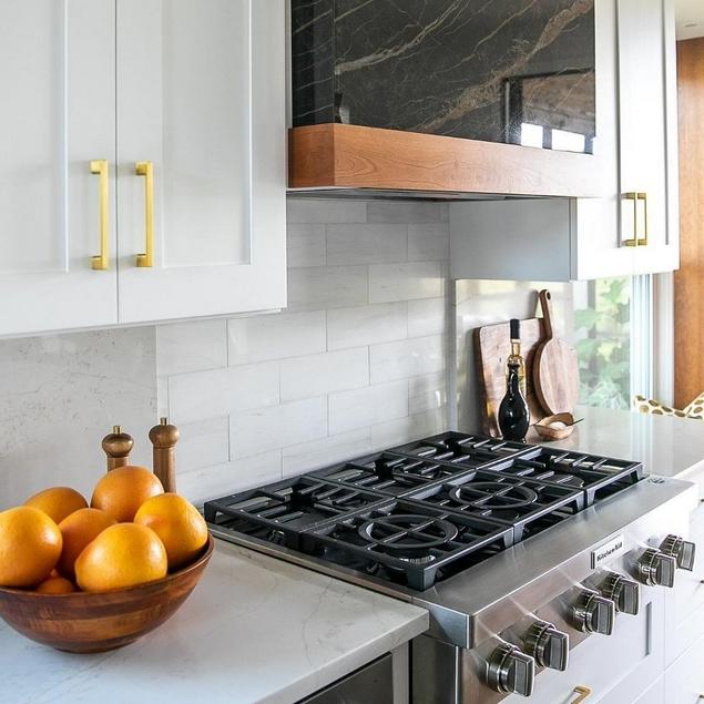 Kitchen close-up of stove, white countertops, white subway tile backsplash, and  white cabinets.