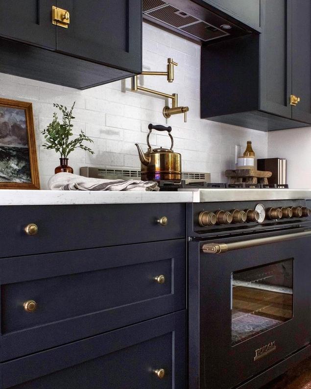 Kitchen with blue cabinets, gold hardware, and white subway tile backsplash.
