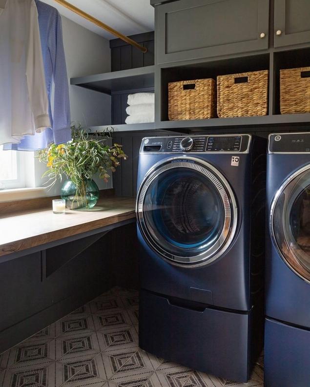 A modern laundry area with cabinets above the washer and dryer as well as patterned flooring tile.