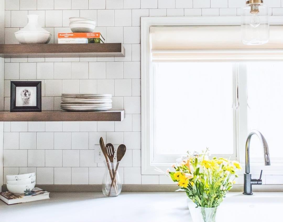 A white kitchen with white subway tile backsplash and open face shelves.
