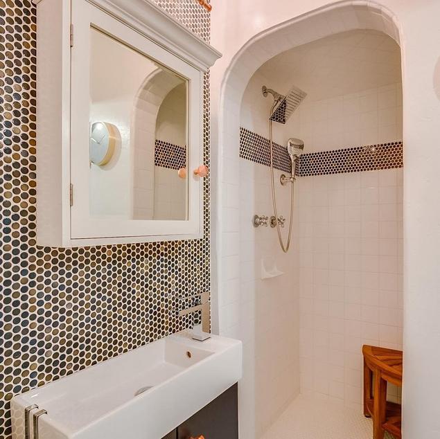 Dark Blue Penny Tile is used as an accent wall and a border around a shower against white tile.