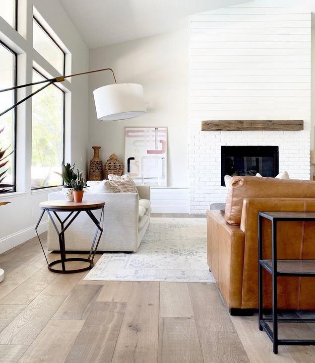 A living room with light blond wood-look flooring and large windows. 