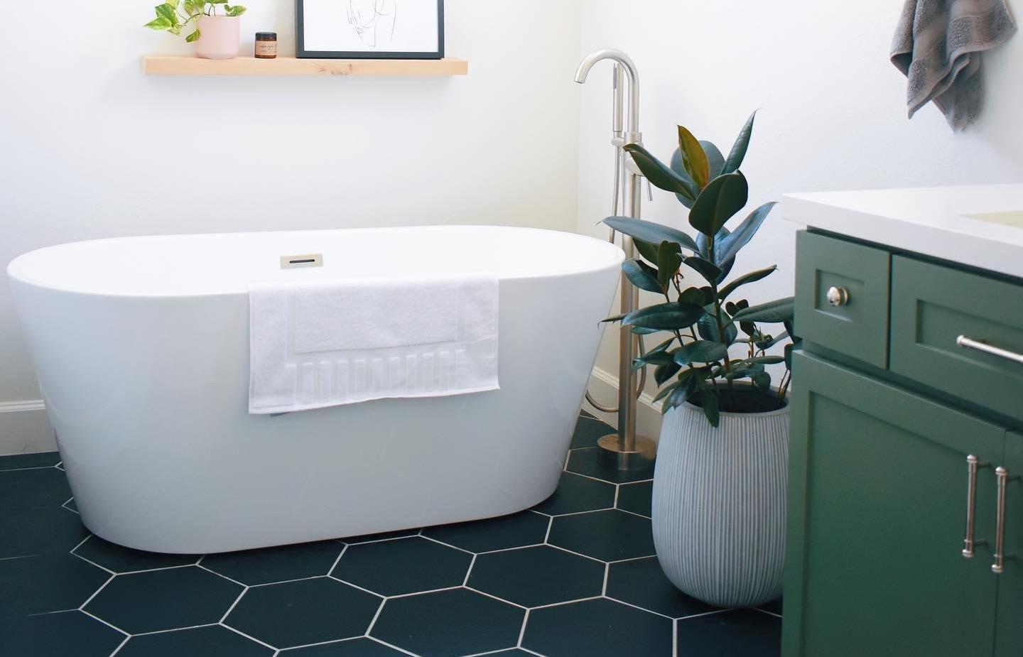 black hexagon tiles in bathroom with white tub and green vanity