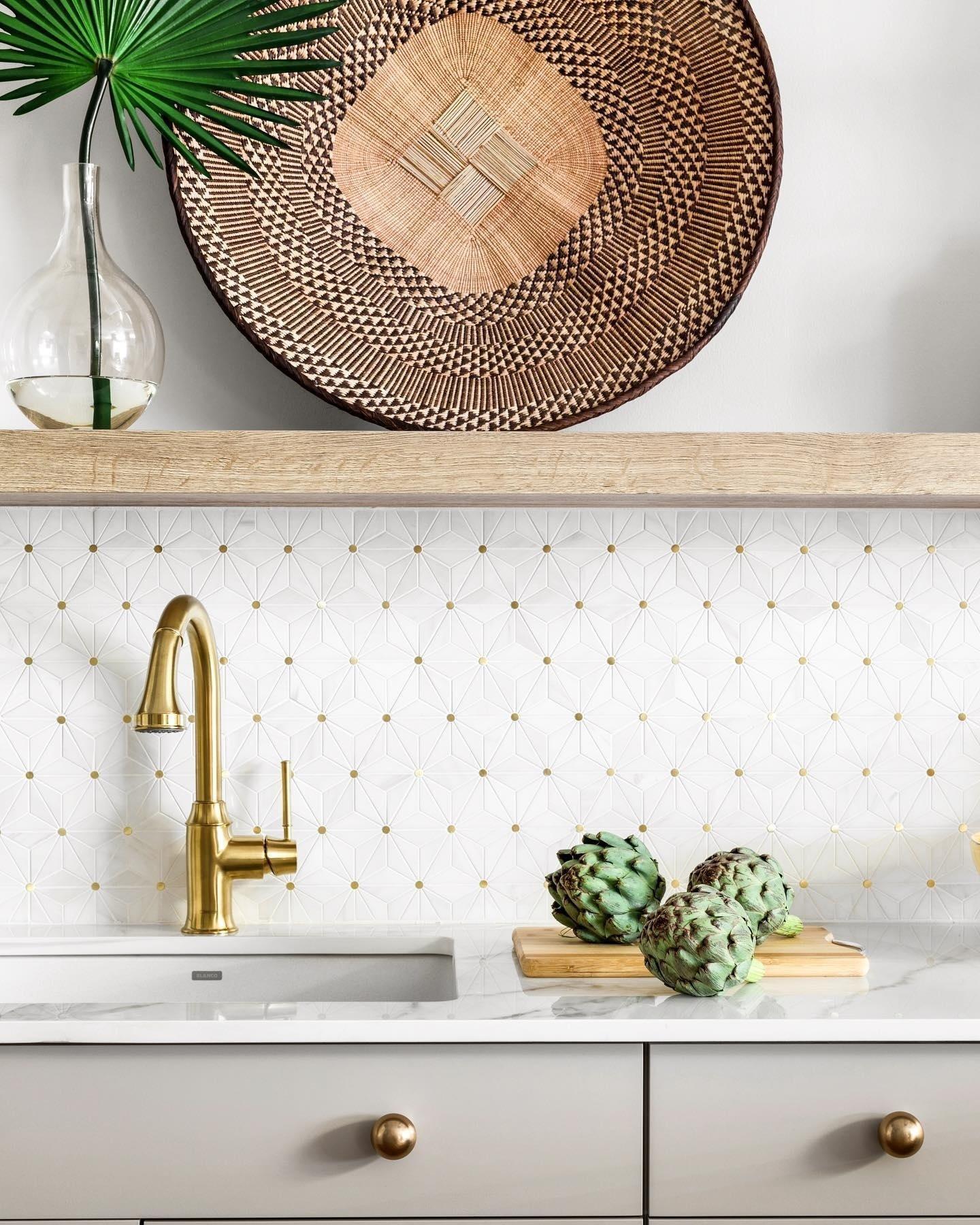 A kitchen backsplash featuring gold accent tile behind a marble countertop