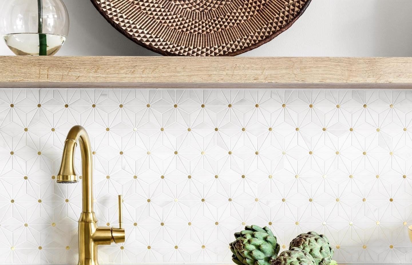 A kitchen backsplash featuring gold accent tile behind a marble countertop