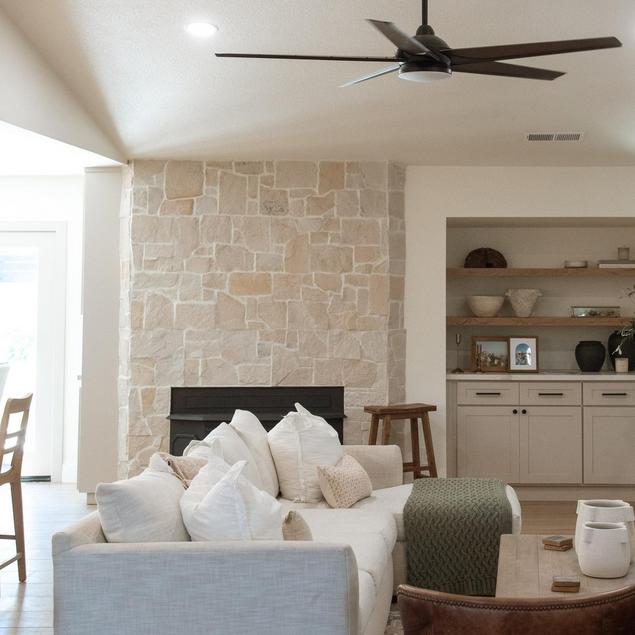 A fireplace with a stone façade and built-in shelves next to it.