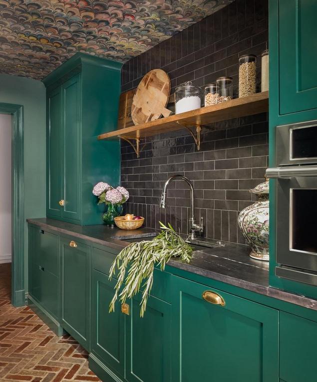 Bold kitchen with black stone backsplash and green cabinetry.