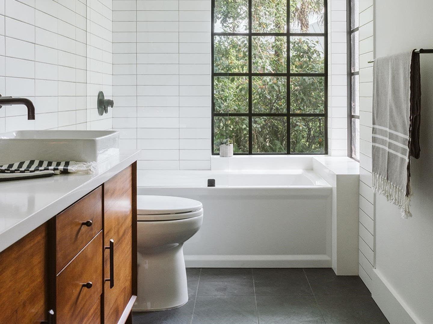 Bathroom with wood vanity, black tile flooring, and white shower wall tile.