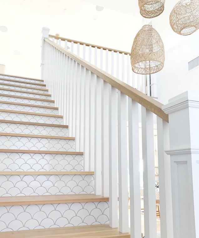 Light brown hardwood staircase with white fan pattern mosaic risers. 