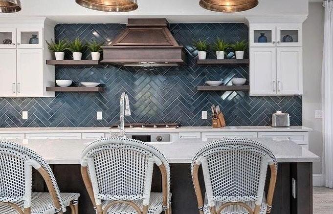 Navy blue backsplash with counter-to-ceiling tile in a herringbone pattern.