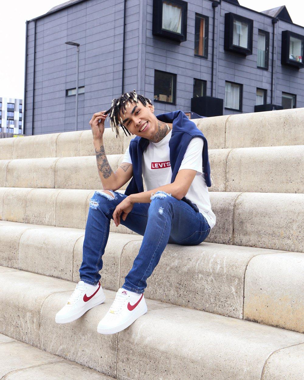 Sitzender Mann auf Treppe, trägt blaue Ripped Skinny Jeans und weißes Levi’s T-Shirt