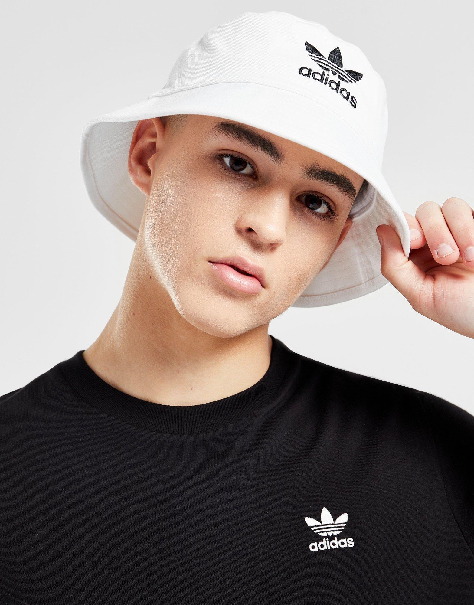 en person i vit bucket hat från adidas