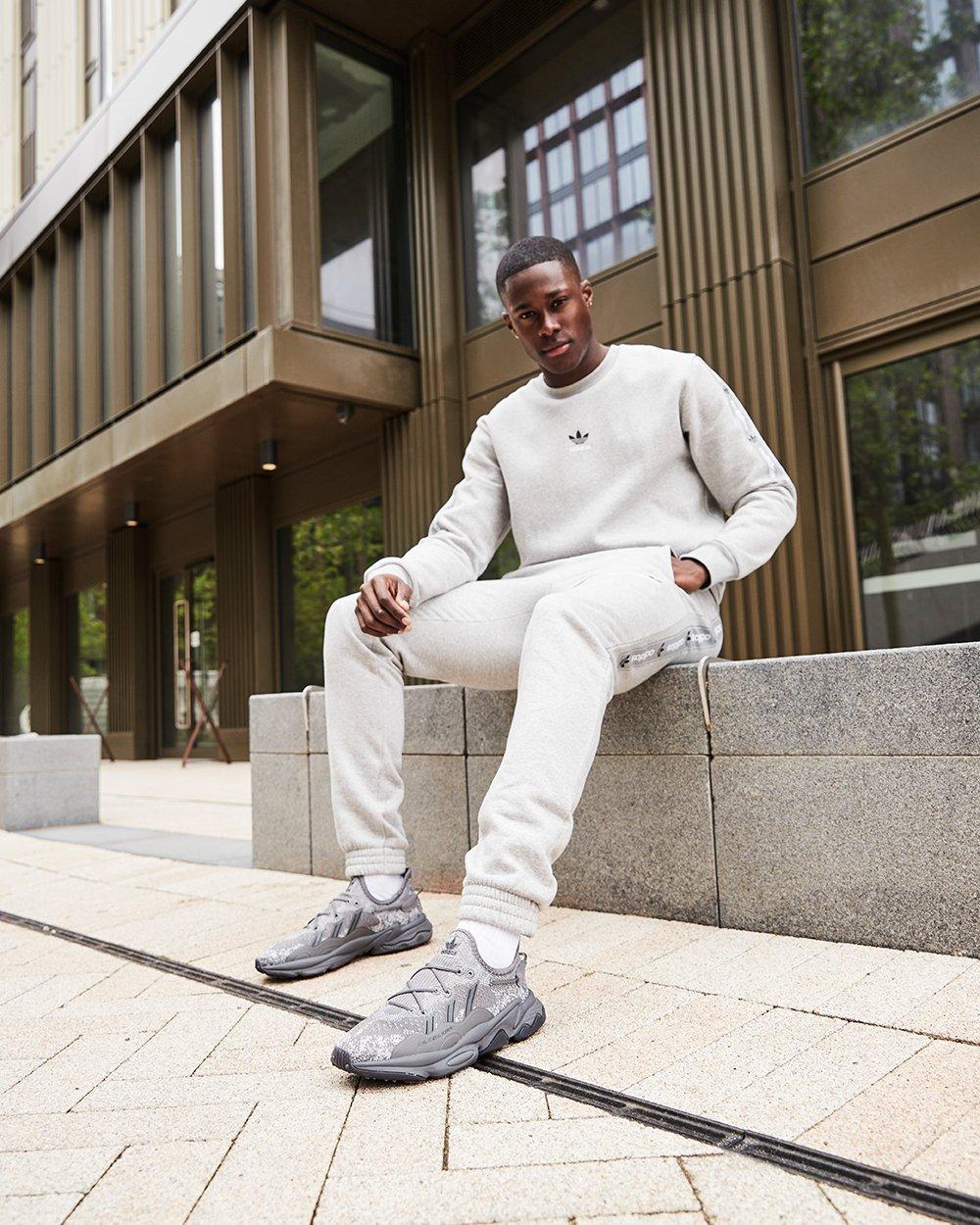 Mann in grauem Trainingsanzug und Ozweego Knit von adidas Originals in Grau