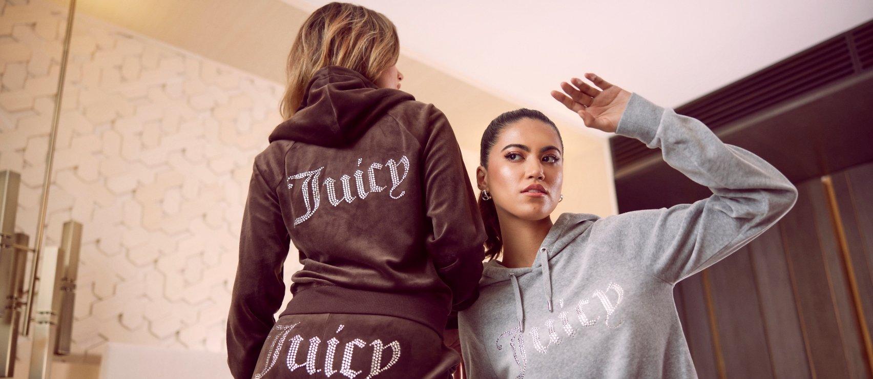 två personer I inomhusmiljö som bär varsin juicy couture-träningsoverall