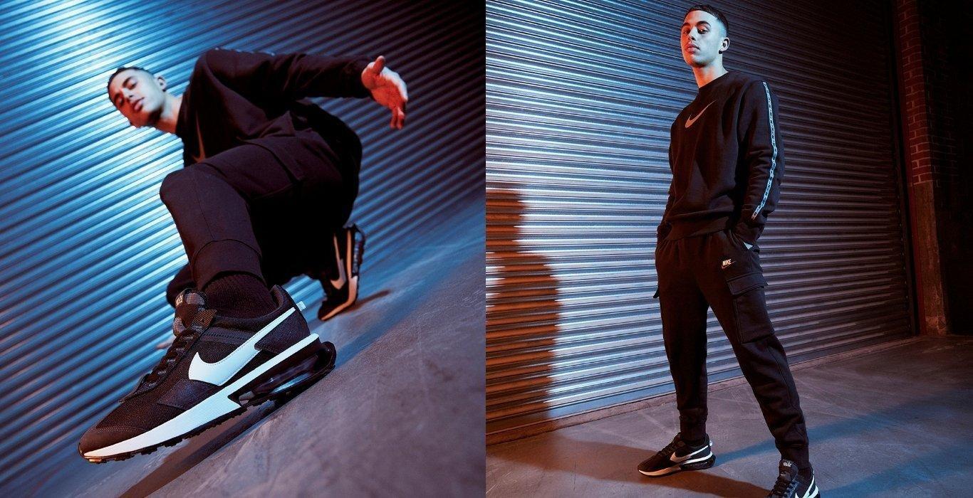 two people wearing dark clothes and black Nike Air Max in a dark indoor environment