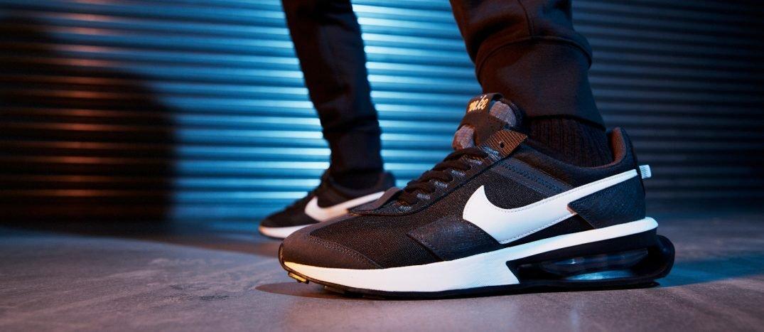 image of the feet and legs of a person wearing black Nike Air Max in a dark indoor environment