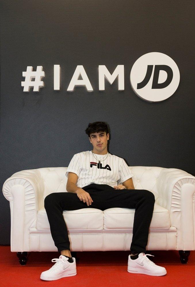 oscar casas con ropa de fila y zapatillas blancas de Nike sentado en un sofa