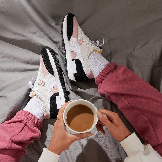 Kvinna med sportiga nike air max 270 skor och en kaffe i sängen